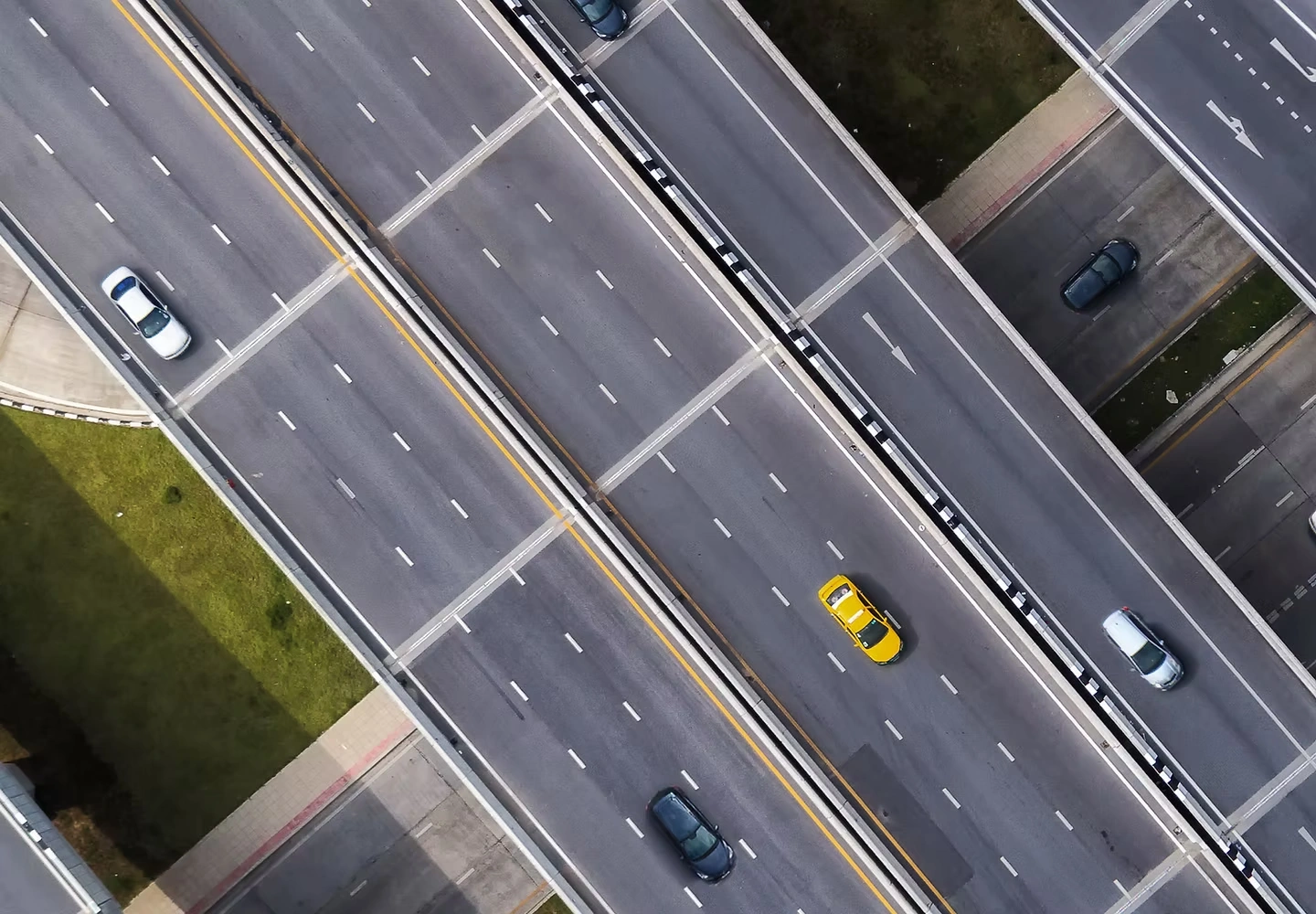 道路與高架橋交錯的俯視圖，多線車道上有汽車行駛，兩側分布綠地與建築。