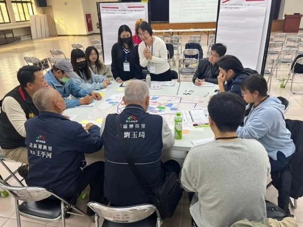 公民參與工作坊現場，參與者圍桌討論地圖，以便利貼整理意見，由主持人引導交流。